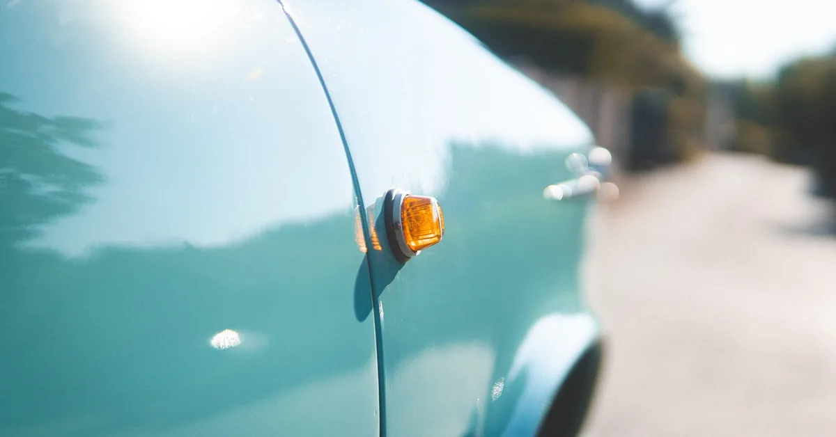 Glossy light blue car fender in sunlight showing the reflective paint finish