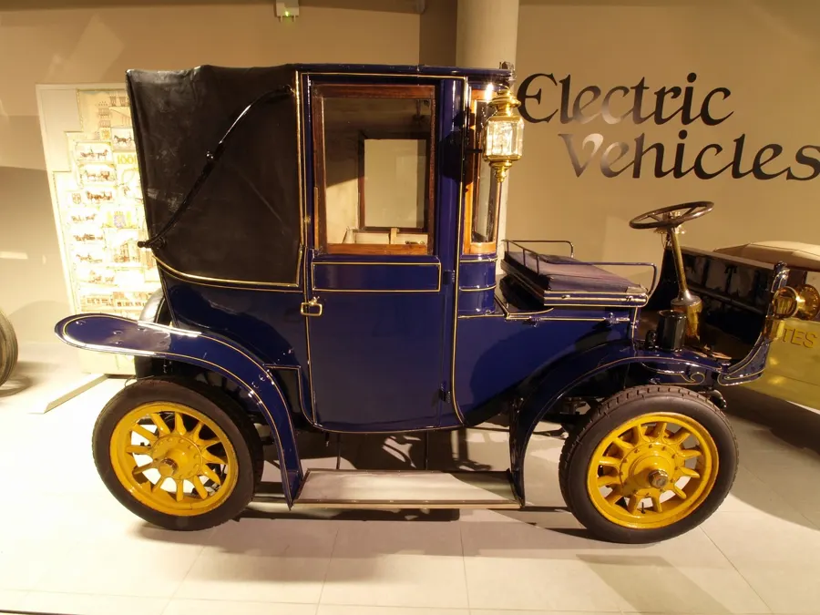 Dark blue 1905 electric brougham car in a museum gallery