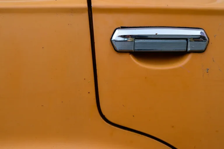 Chrome pull-style exterior door handle on an orange car door