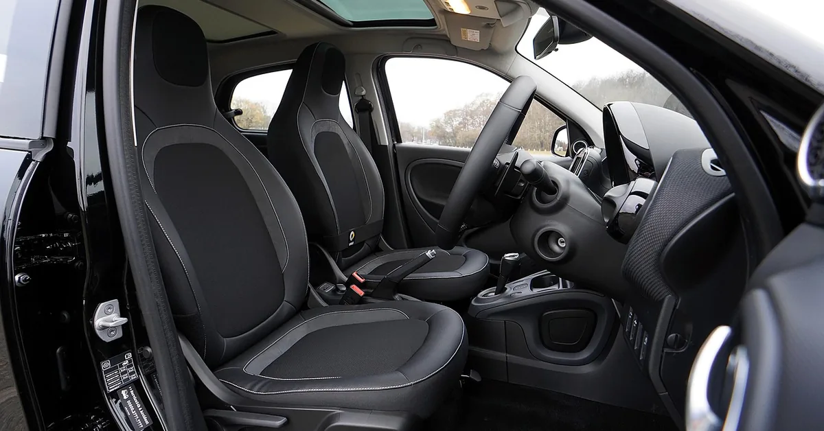 Clean black front seats and dashboard seen through an open car door