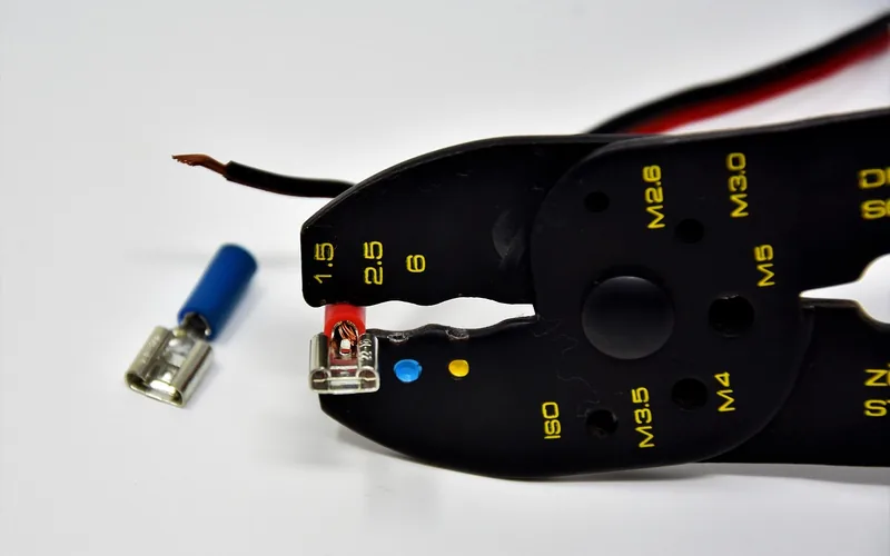 Crimping pliers holding a red wire in a blue insulated female spade terminal Crimping pliers holding a red wire in a blue insulated female spade terminal