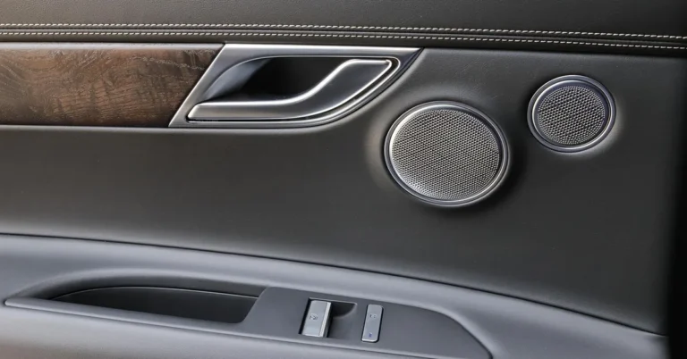 Car door interior panel showing the inside handle, speaker grilles and window switches
