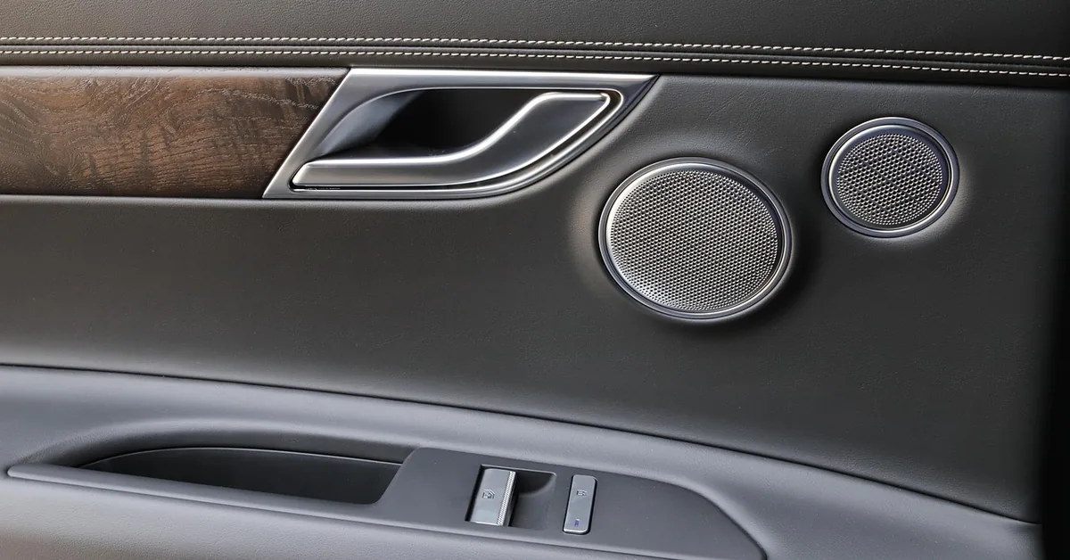 Car door interior panel showing the inside handle, speaker grilles and window switches