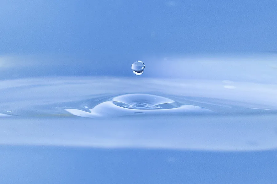 A water drop falling into still water and making ripples
