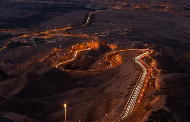 Winding mountain road at dusk with light trails left by passing vehicles