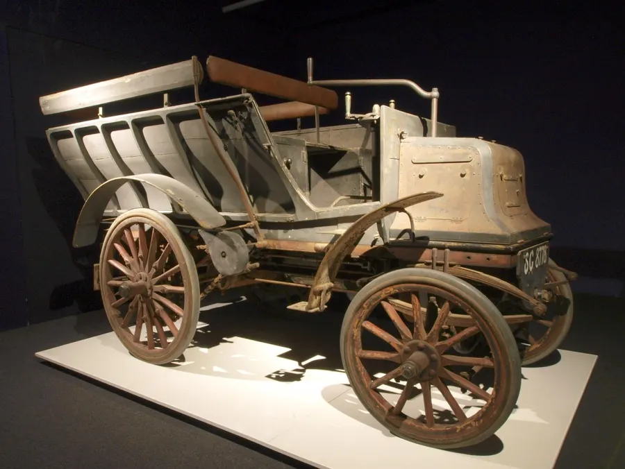 Early motor car with wooden wheels on display in a museum