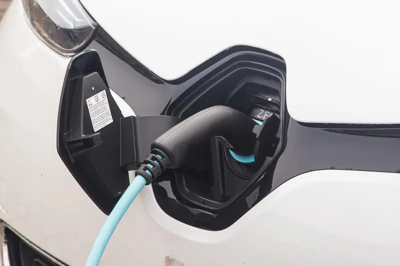 Charging plug inserted into the charge port of a white electric car
