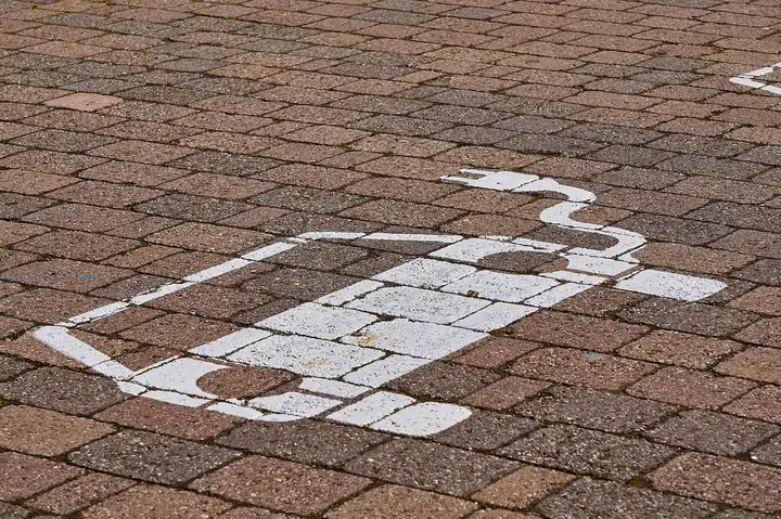 Electric vehicle charging bay symbol painted on brick pavement