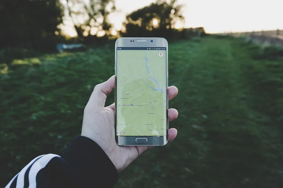 Hand holding a smartphone that shows a map on its screen