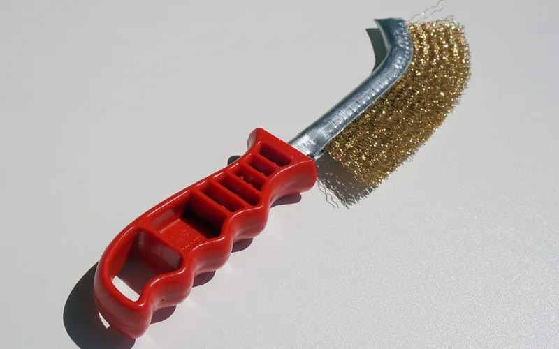 Hand wire brush with brass bristles and a red handle
