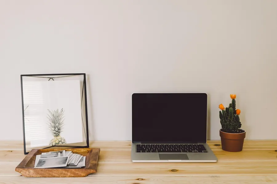 Laptop open on a wooden desk with a small tray of papers