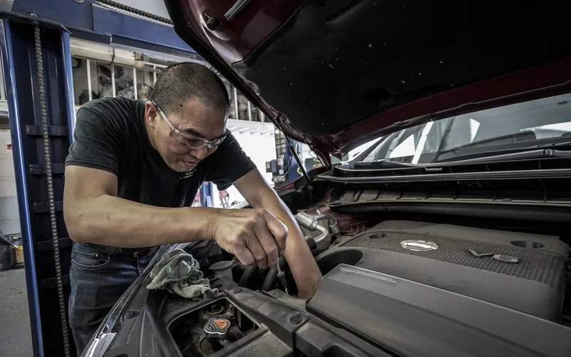 Mechanic working under the hood of a car during routine oil change maintenance