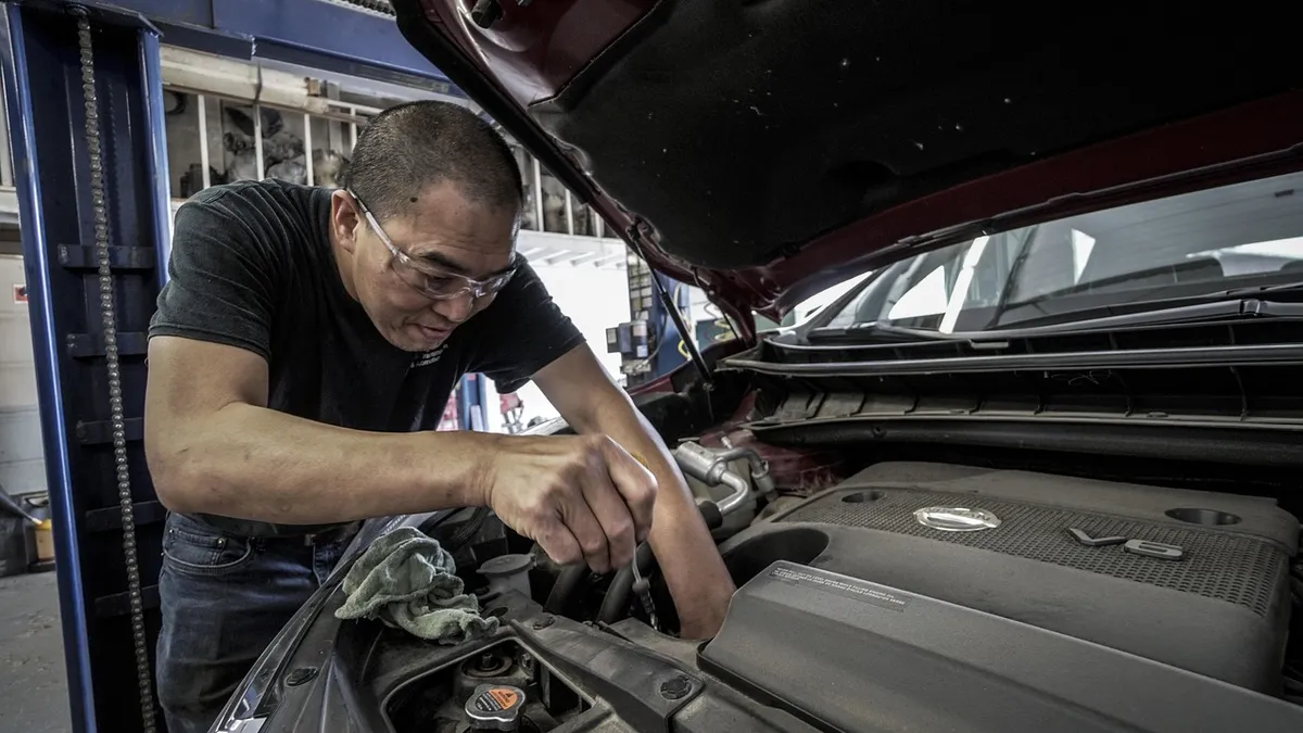 Mechanic leaning into an open engine bay during a vehicle service