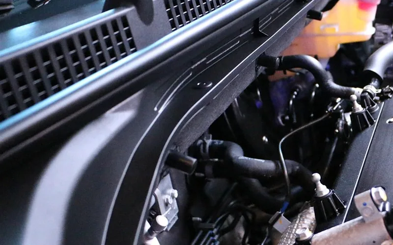 Close view inside an open car hood showing the coolant reservoir, hoses and edge of the engine