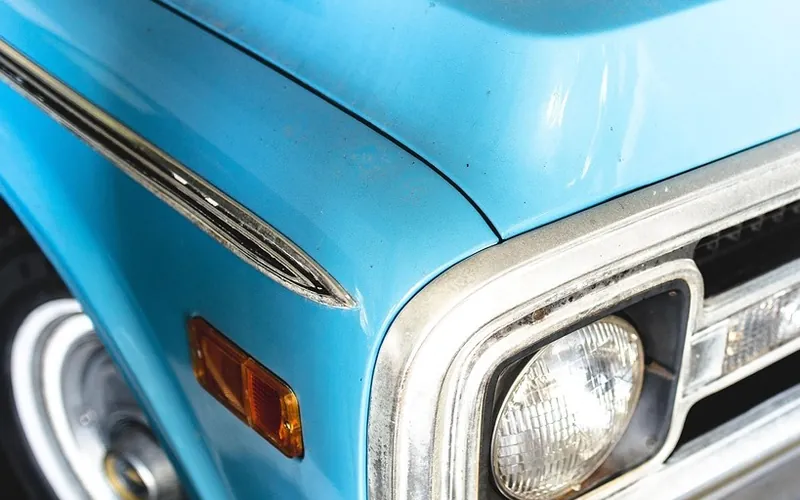Painted hood and front fender edge beside a round headlight