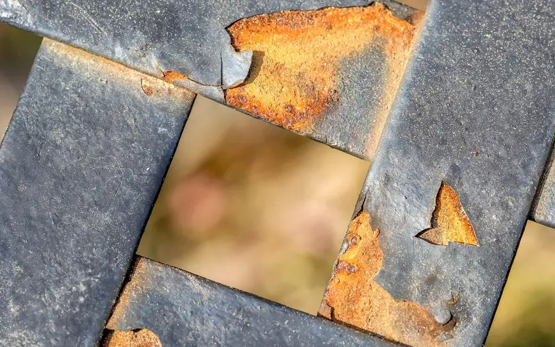 Orange rust patches where paint has flaked off dark painted steel strips