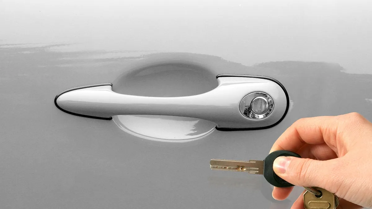 Hand unlocking a car door with a key when there is no interior access