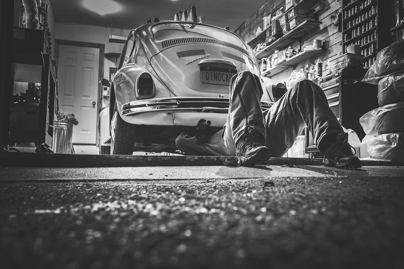 Mechanic working underneath a car in a repair shop bay