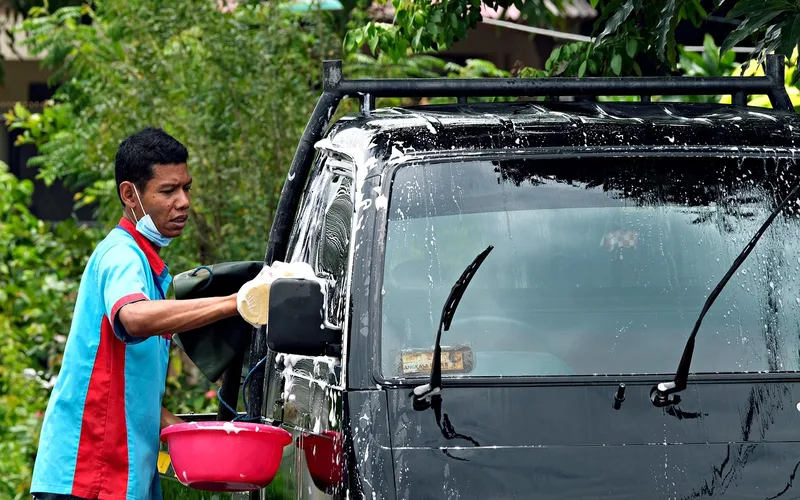 Hand washing a freshly painted car with a microfiber mitt and pH-neutral soap