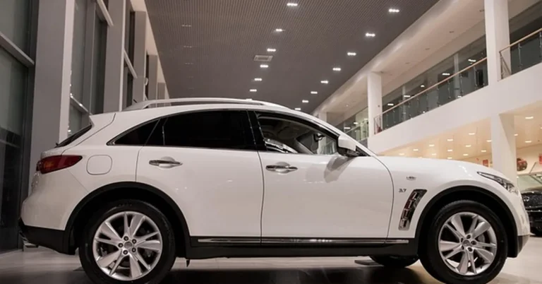 White SUV parked inside a modern new car dealership showroom