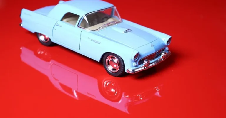 Blue diecast collectible toy car on a reflective surface