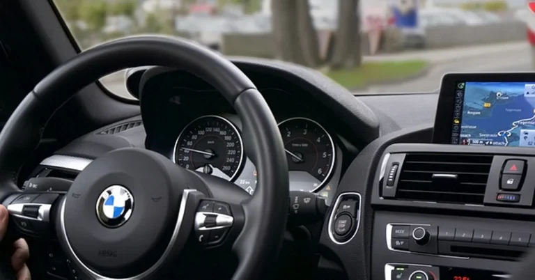 BMW steering wheel and dashboard with the iDrive navigation screen used to access Lane Assist settings