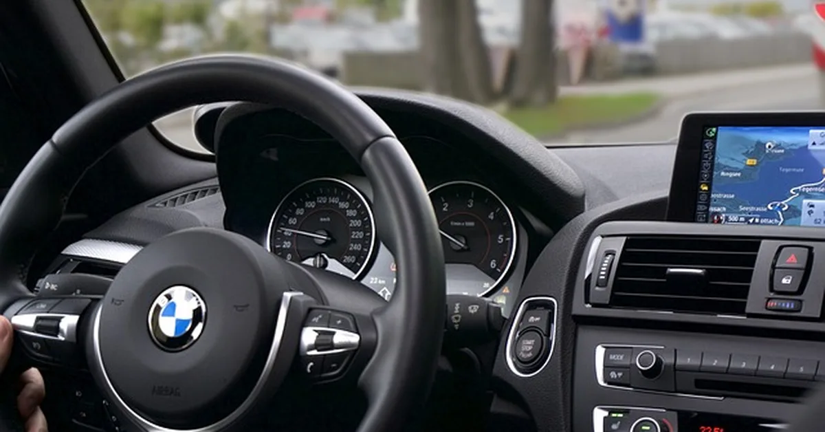 BMW steering wheel and dashboard with the iDrive navigation screen used to access Lane Assist settings