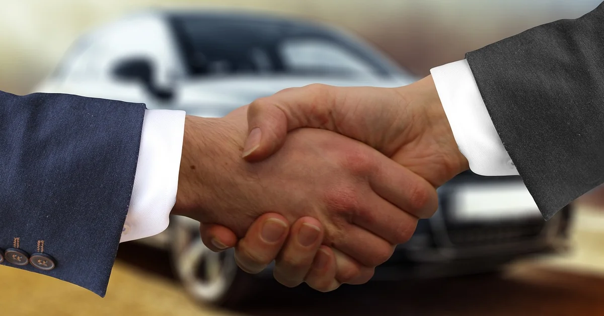 Car dealer and buyer shaking hands over a contract showing car dealer fees