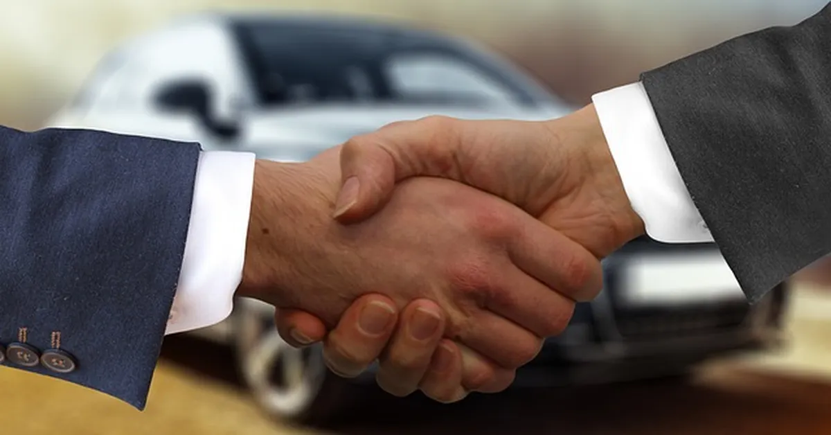 Handshake between a buyer and dealer finalizing a car loan