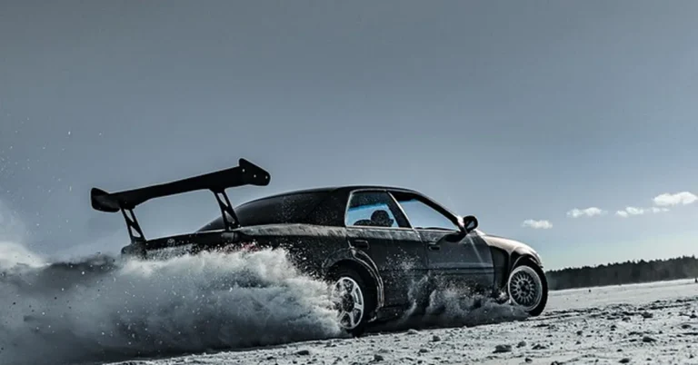 Car with a rear spoiler wing sliding through snow, showing aerodynamic control
