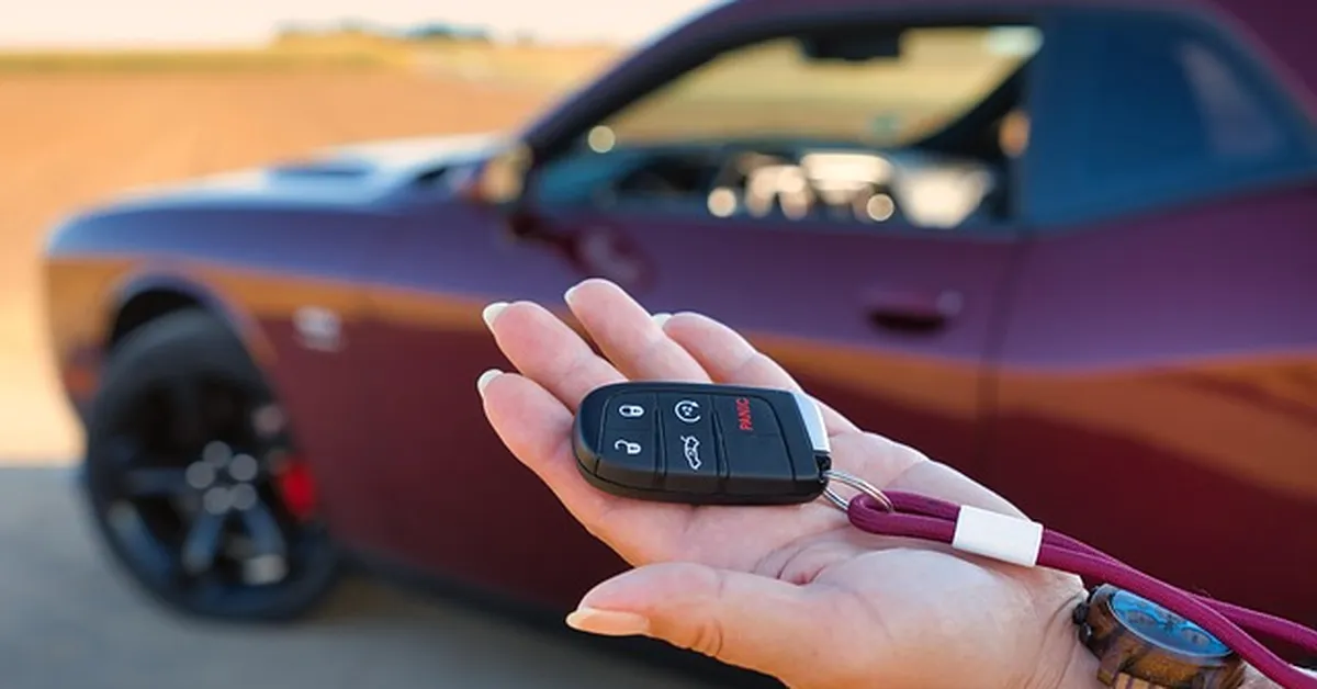 Car key fob held in front of a parked car