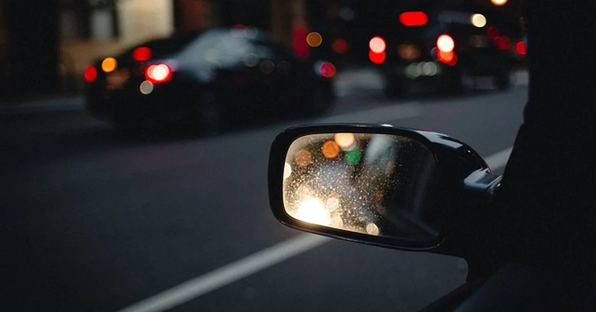Car side mirror reflecting traffic at night