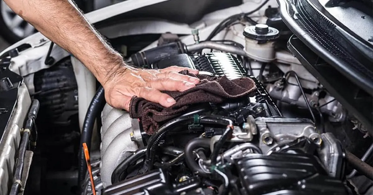 Mechanic hand wiping car engine bay during service