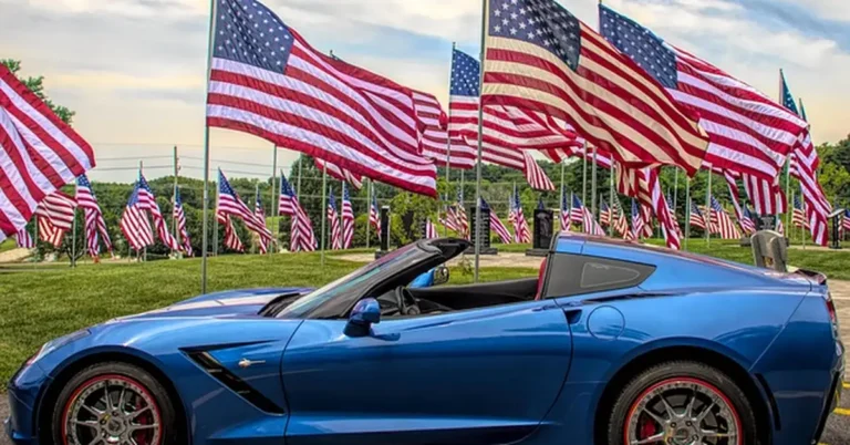 Blue sports car parked in front of a row of American flags