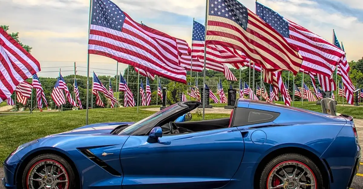 Blue sports car parked in front of a row of American flags