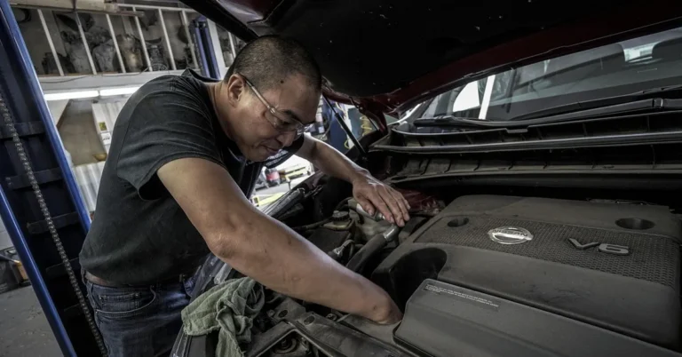 Mechanic inspecting a car engine during a warranty repair visit