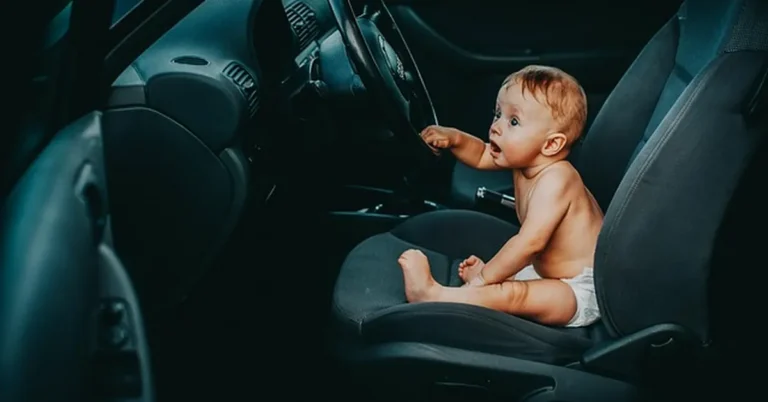 Baby sitting in a car seat near the steering wheel