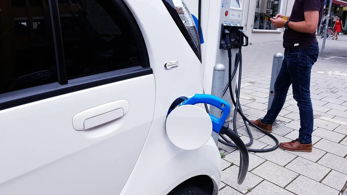Electric vehicle plugged into a public charging station terminal