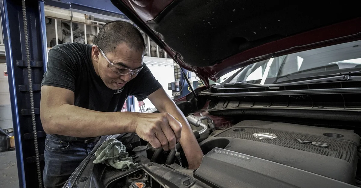 Mechanic servicing a vehicle rear differential and axle under the hood