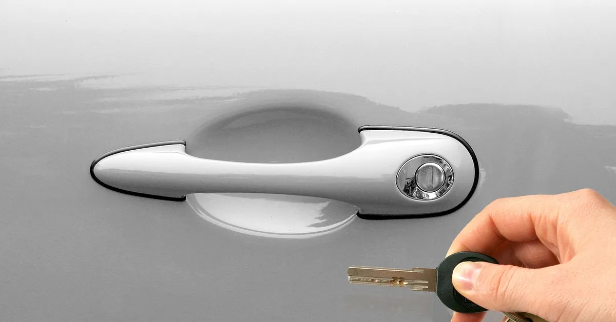 Hand unlocking a car door with a rental car key