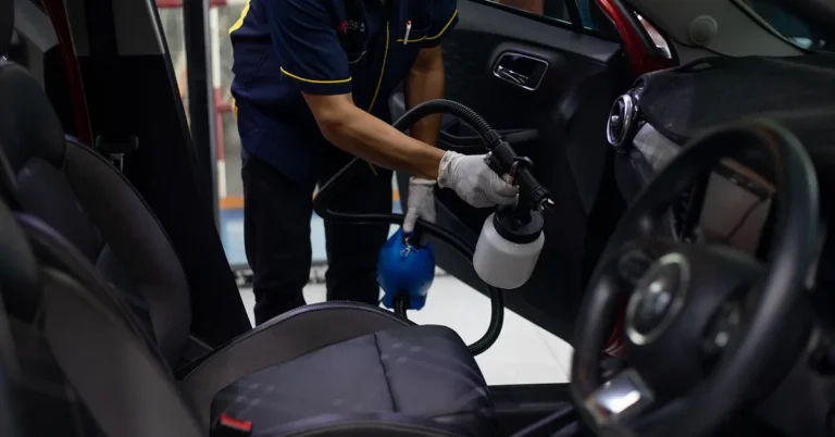 Detailing technician drying a car interior with a sprayer