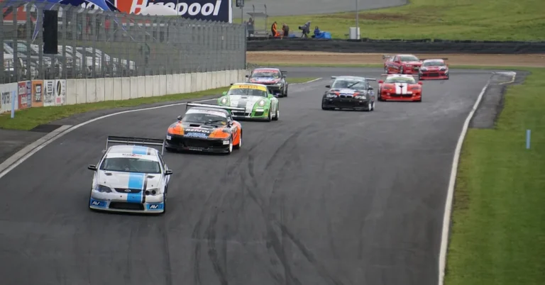Pack of race cars speeding around a motorsport track