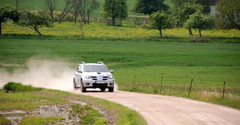 SUV kicking up dust while driving on a rural dirt road