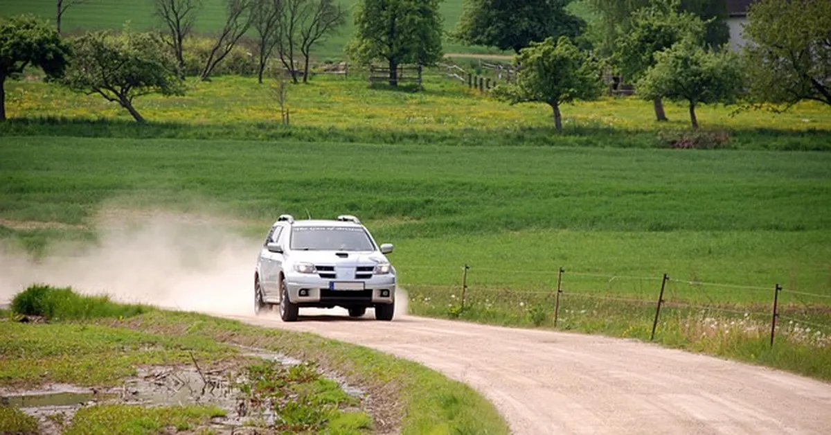 SUV kicking up dust while driving on a rural dirt road