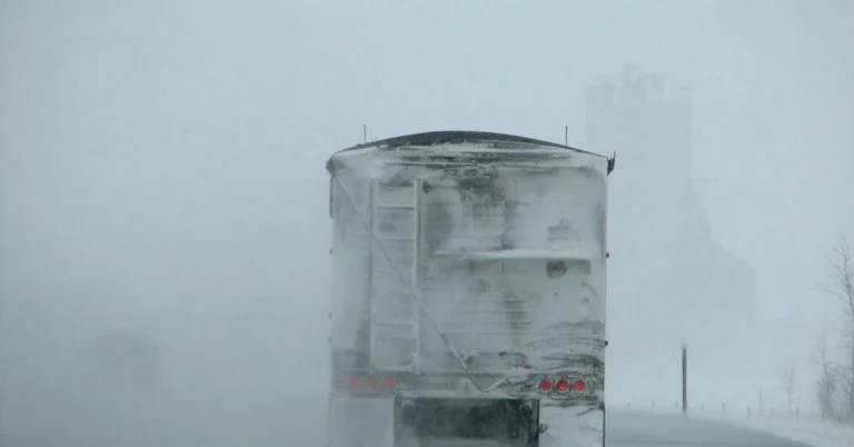 Truck driving on a snowy, low-visibility road