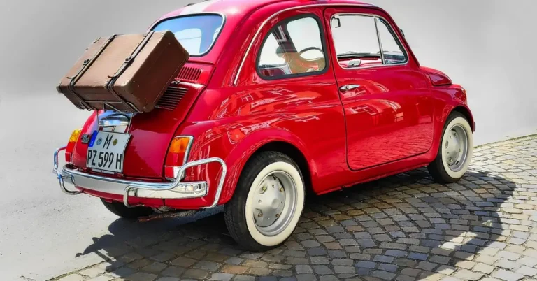 Vintage red car with a small sunroof and rooftop luggage