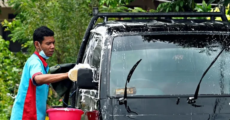 Man washing a car by hand with soap and sponge