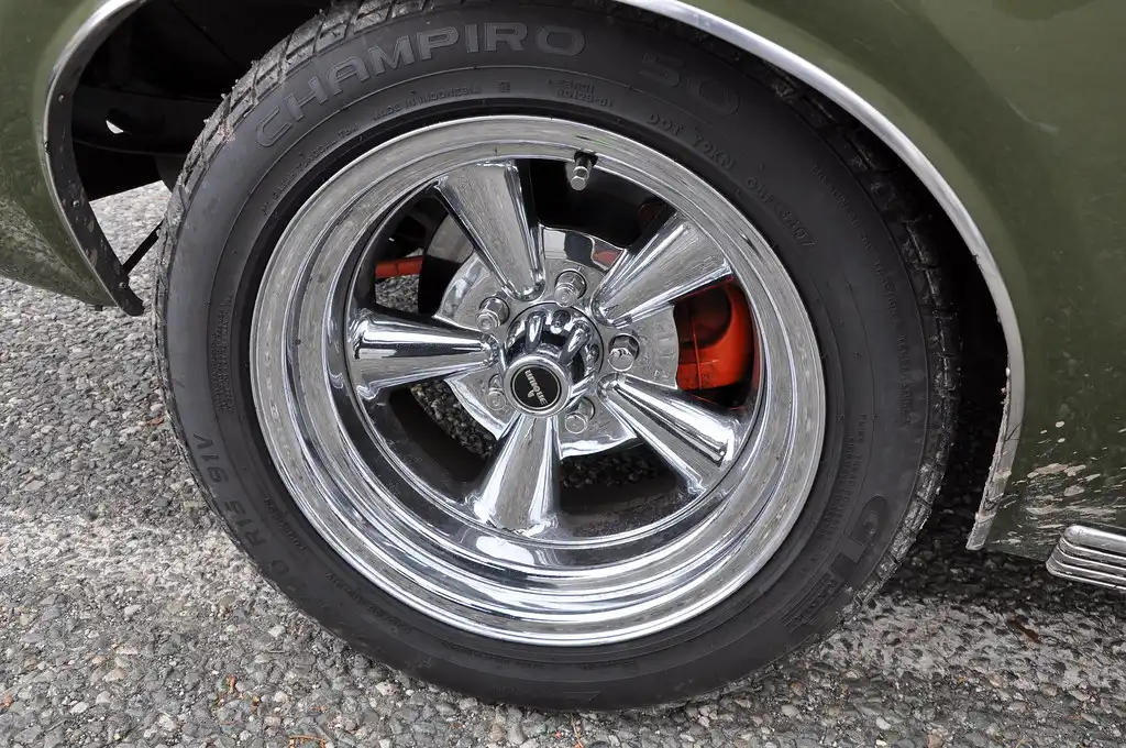 Close-up of all-season tire tread beside a touring tire tread on a driveway