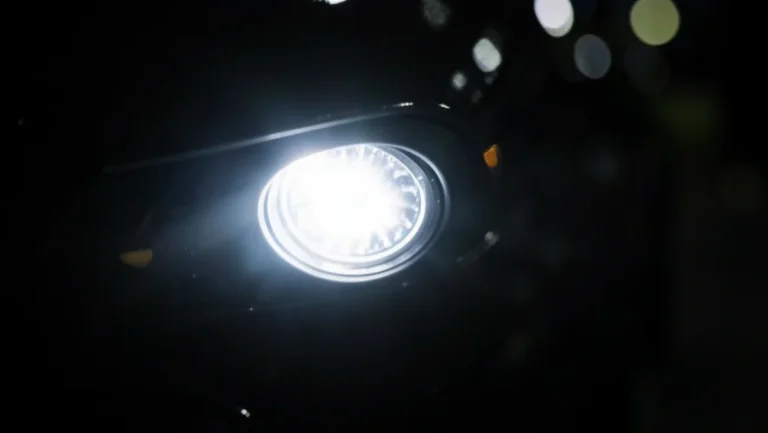 Close-up of a car headlight glowing with a bright white LED beam at night
