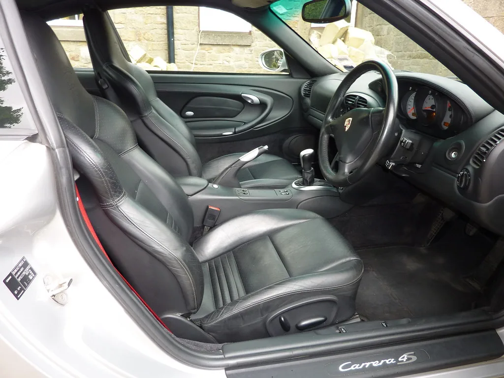 Microfiber towel cleaning a dusty car dashboard vent and textured trim